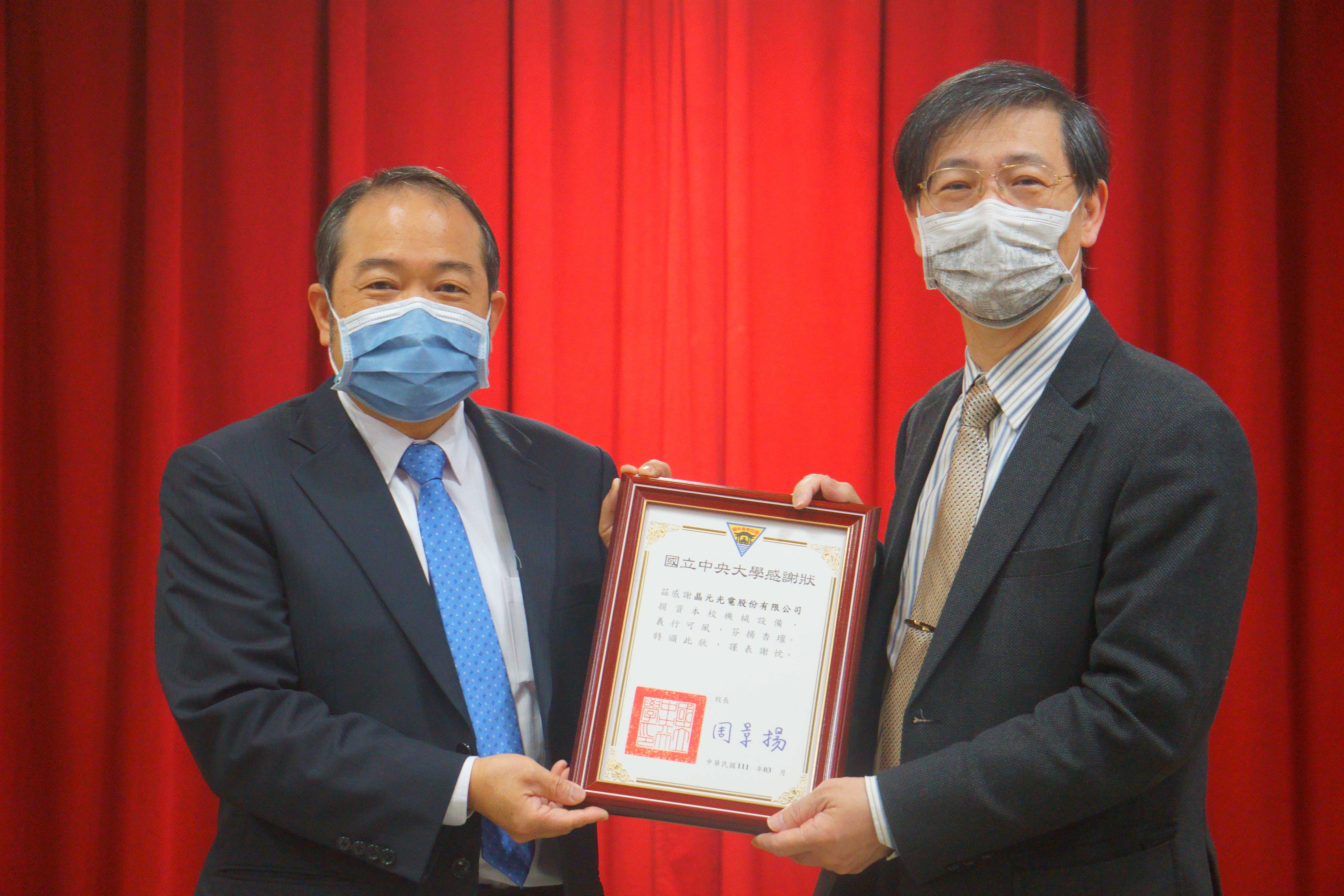綦振瀛副校長(右)代表全體師生致贈感謝狀給晶元光電范進雍董事長(左)。照片理學院提供。