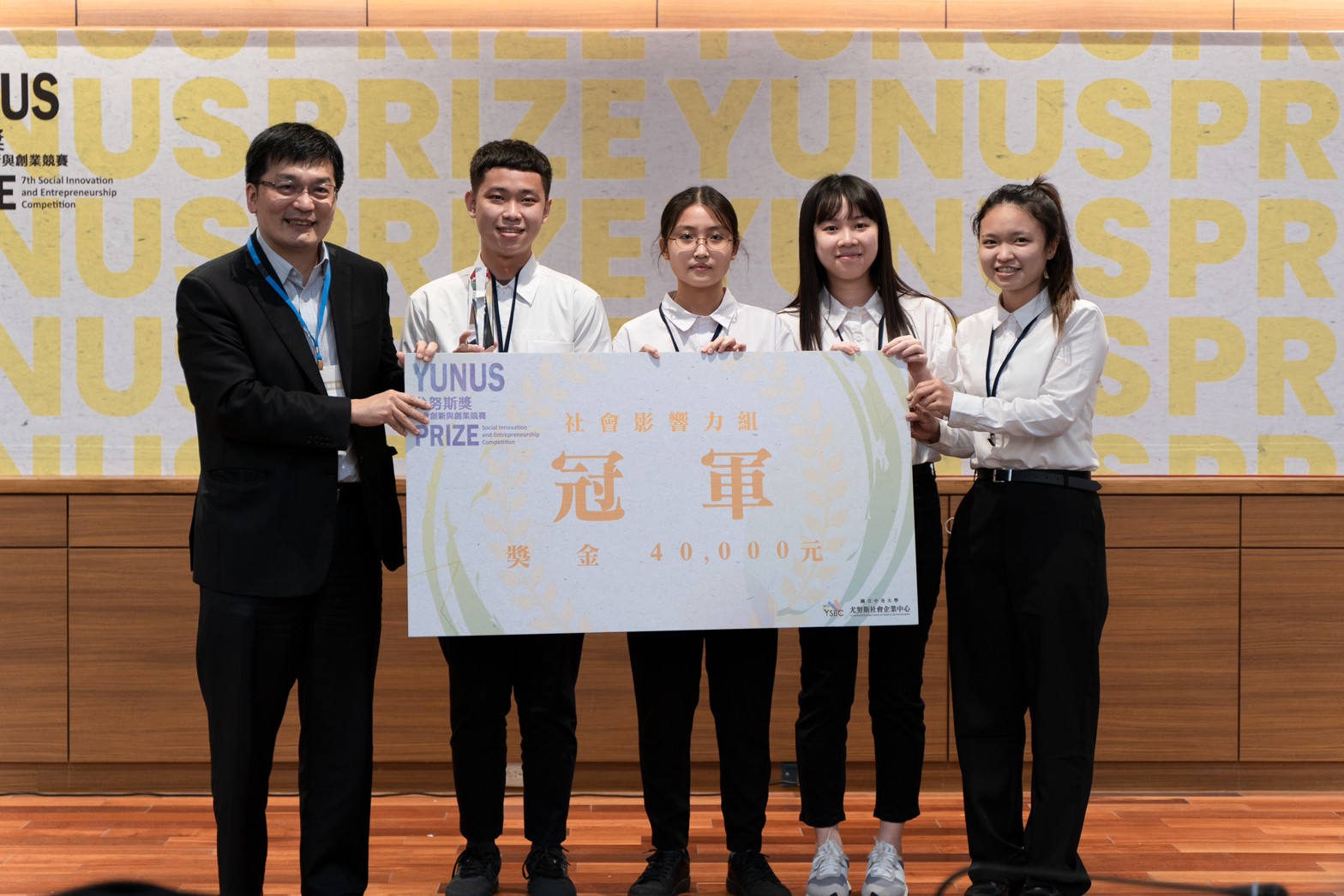 第七屆社會影響力組由「【SDGs4】USR hub看見需要千手扶學志工團隊」團隊奪得冠軍,由國立中央大學尤努斯社會企業中心主任沈建文(左一)頒獎。照片尤努斯社企中心提供