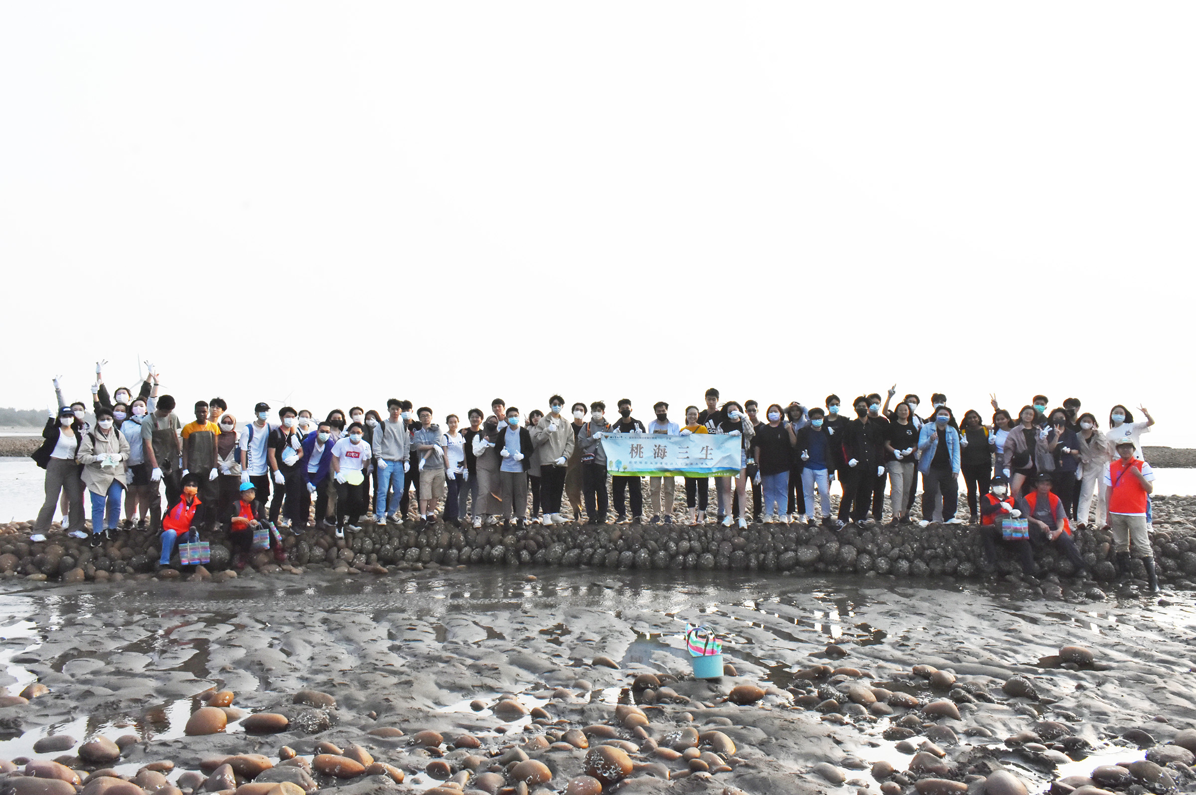 全體師生與外籍生開心於石滬上合影。照片教發中心提供