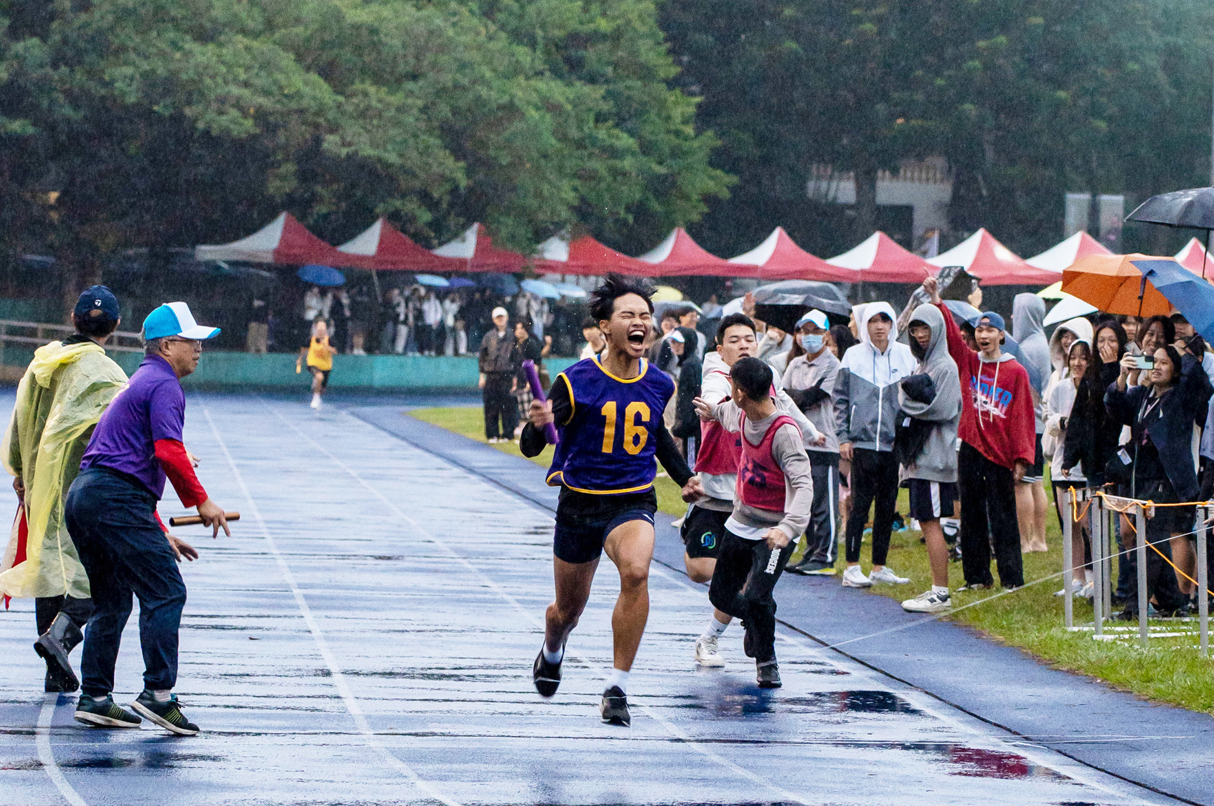 大隊接力時下雨，但澆不熄場上沸騰的熱血；在雨中馳騁，彰顯了同學不畏艱難、不屈不撓的決心。蔣以新攝