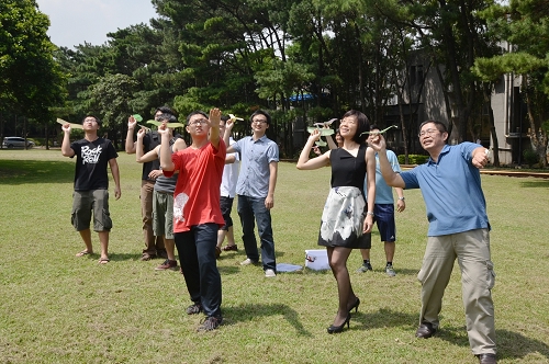 卓志賢老師(右一)和朱慶琪老師(右二)，帶領同學在戶外草坪展開紙飛機擲射，享受飛翔樂趣。石孟佳攝