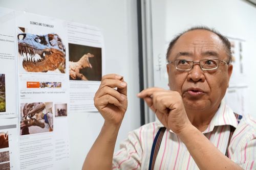 Dr. Rong-Seng Chang, Prof. of the Dept. of Optics and Photonics, holding a tooth fossil of Tyrannosaurus, explains that the internal structures of the saw-like cutting edges on theropod dinosaurs’ teeth are like springs which protect their teeth from cracking easily and make them top hunters. 