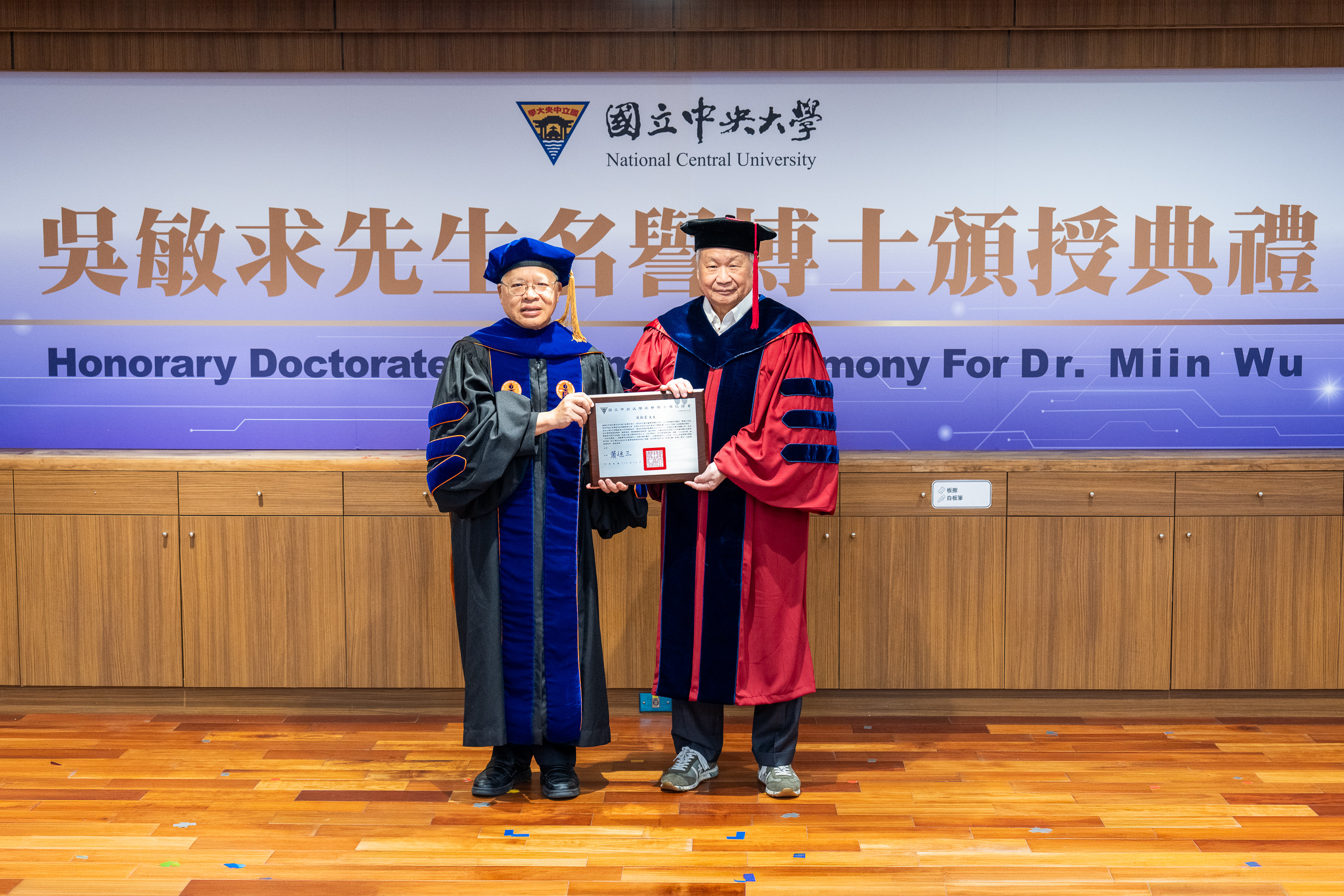 中央大學校長蕭述三（左）頒授名譽博士學位證書給旺宏電子創辦人暨董事長吳敏求先生（右），表彰他對台灣科技自主、產業創新及人才培育之卓越貢獻。照片秘書室提供
