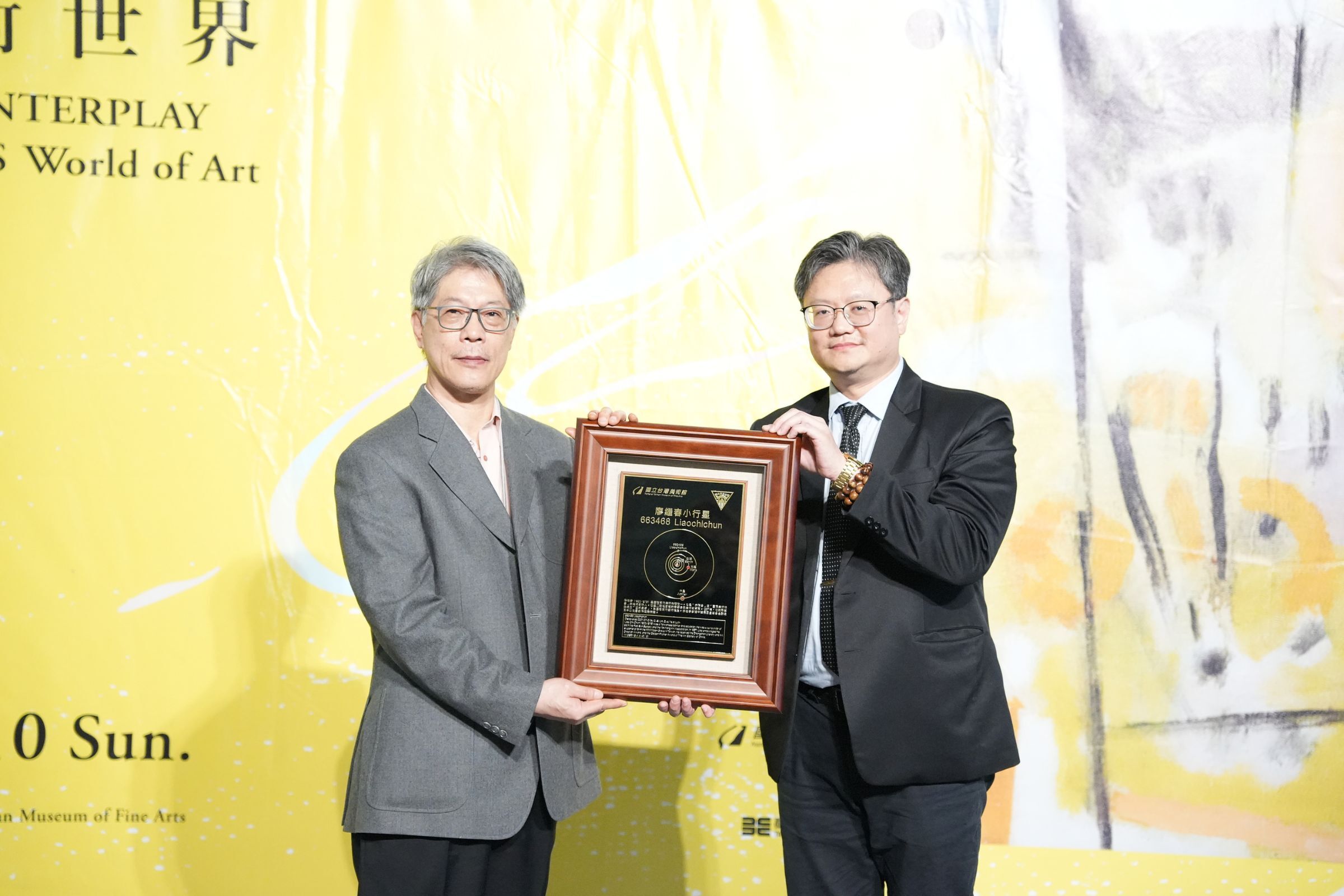 國立中央大學主任秘書李宇翔（右）致贈小行星銘版給廖繼春的家屬代表廖和恩先生（左）。陳如枝攝